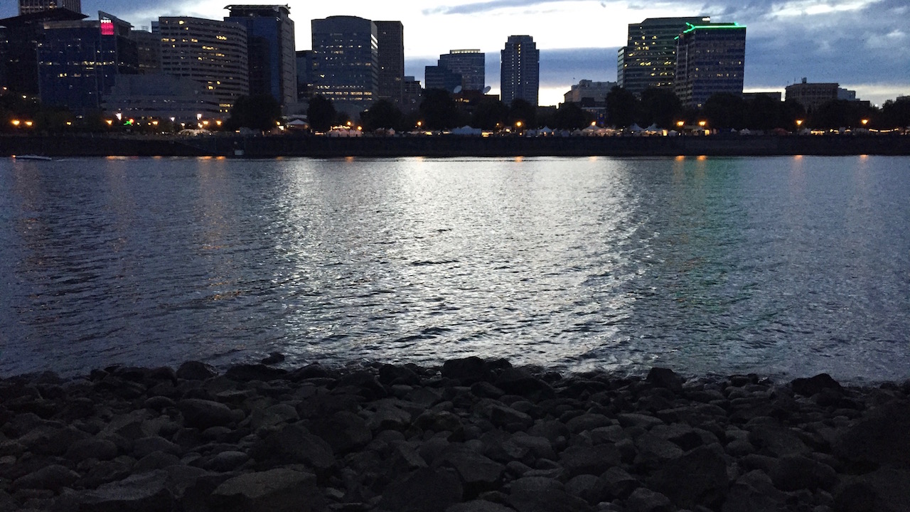 A city skyline over a river at dusk