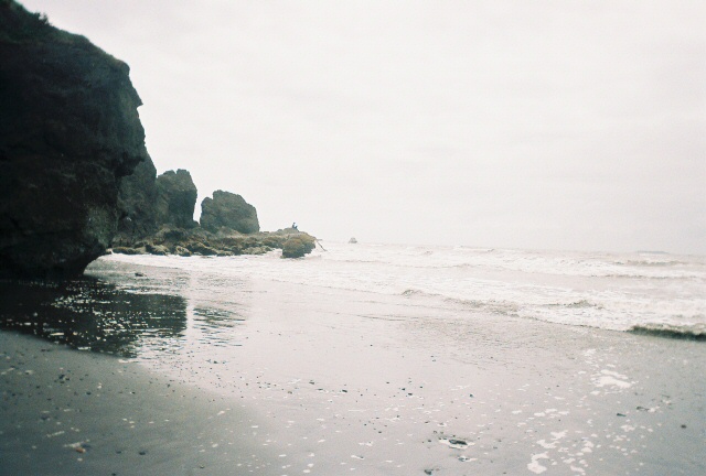 Rocky coast, very small figure on a rock out in the water